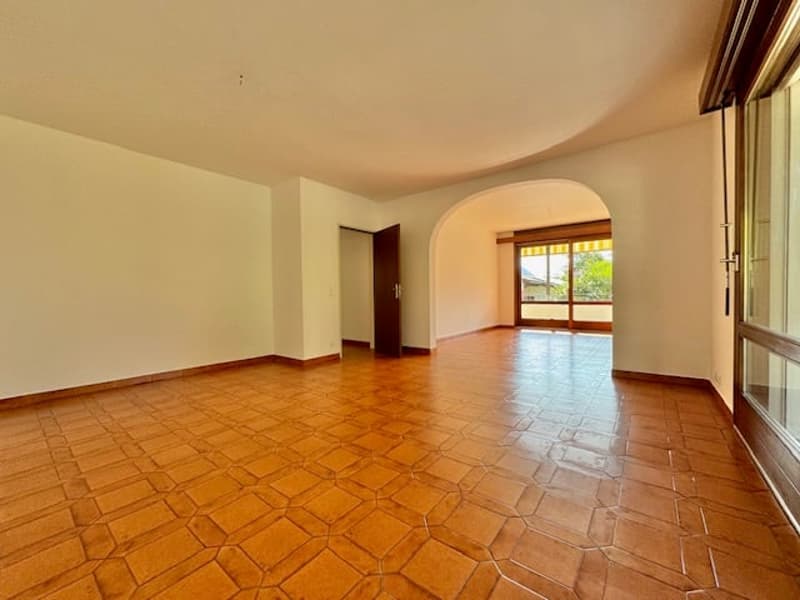 spacious room, tiled floor, sliding glass door, arched entry, natural light from windows