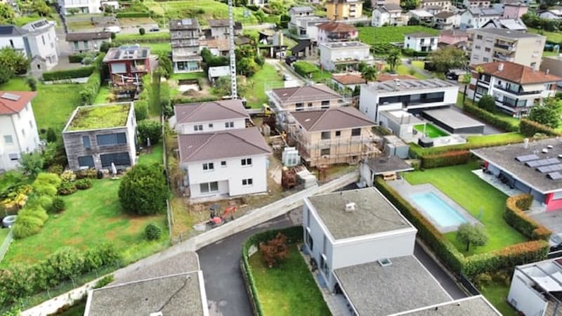 Multiple houses, some under construction, swimming pool, green grass, large gardens, driveway