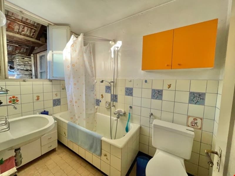 Bathtub, sink, toilet, white walls, white tiles, orange cabinets