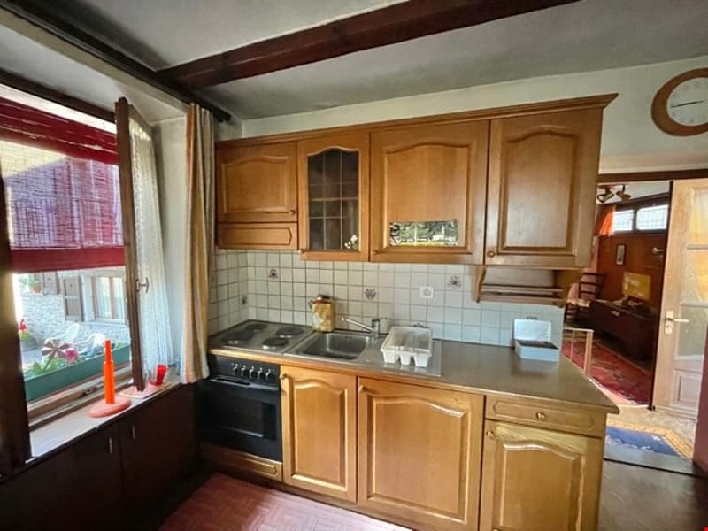 kitchen with natural light, wooden cabinets, gas stove, sink, electric hobs, clock on wall, wooden flooring, window with red blinds, flower pot on window sill