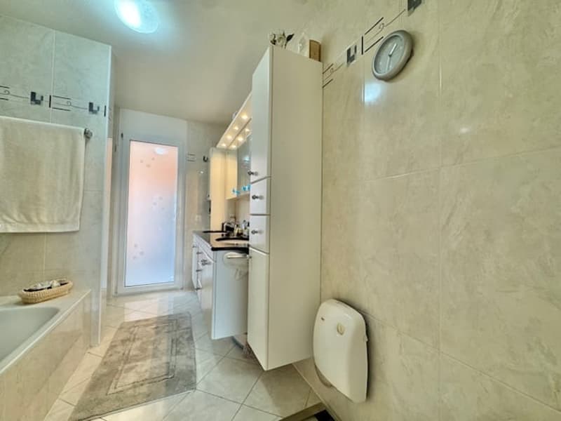 Tiled bathroom with a washing machine, sink, and toilet.