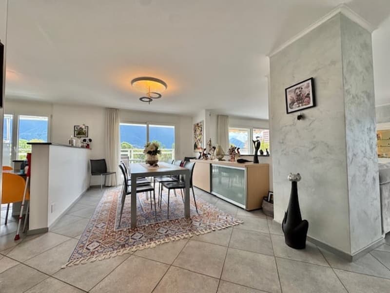 Open-concept living and dining area with large windows, hardwood floors, modern furniture, and a decorative rug