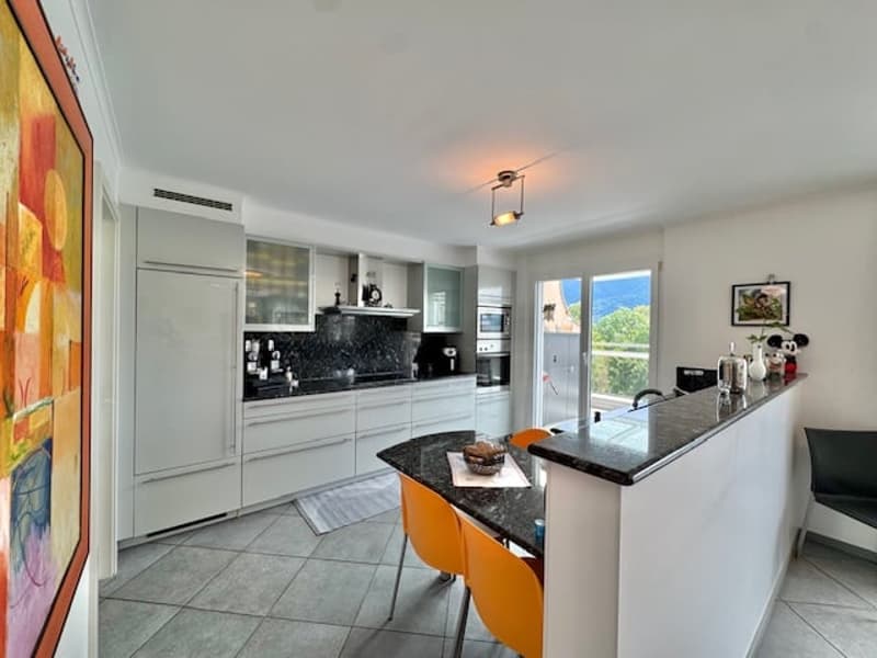 Modern kitchen with white cabinets, black granite countertops, tiled floor, and a dishwasher visible.