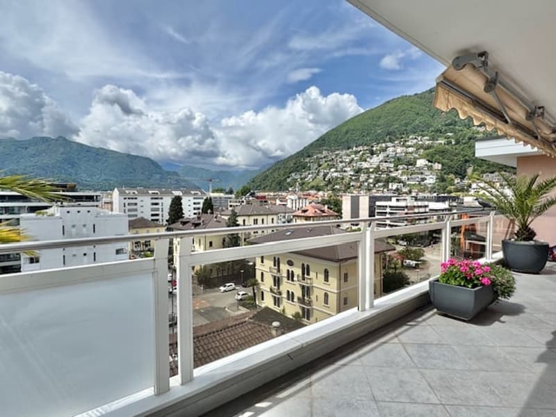 Balcony with a view of a city surrounded by mountains and cloudy sky