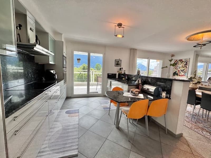Spacious open-concept kitchen with modern appliances, black countertops, and sliding glass doors leading to a balcony or terrace.