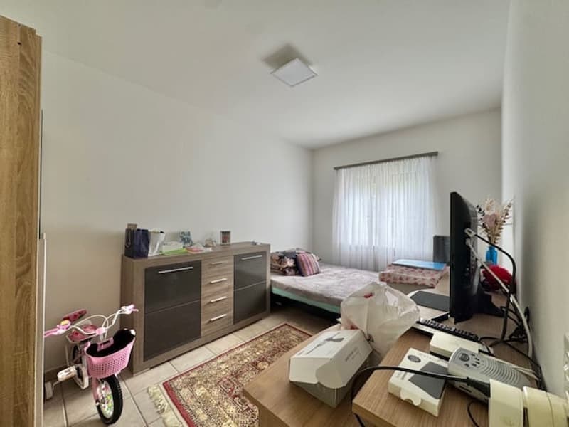 Bedroom with a bed, dresser, and other furniture. There is a washing machine visible in the room.