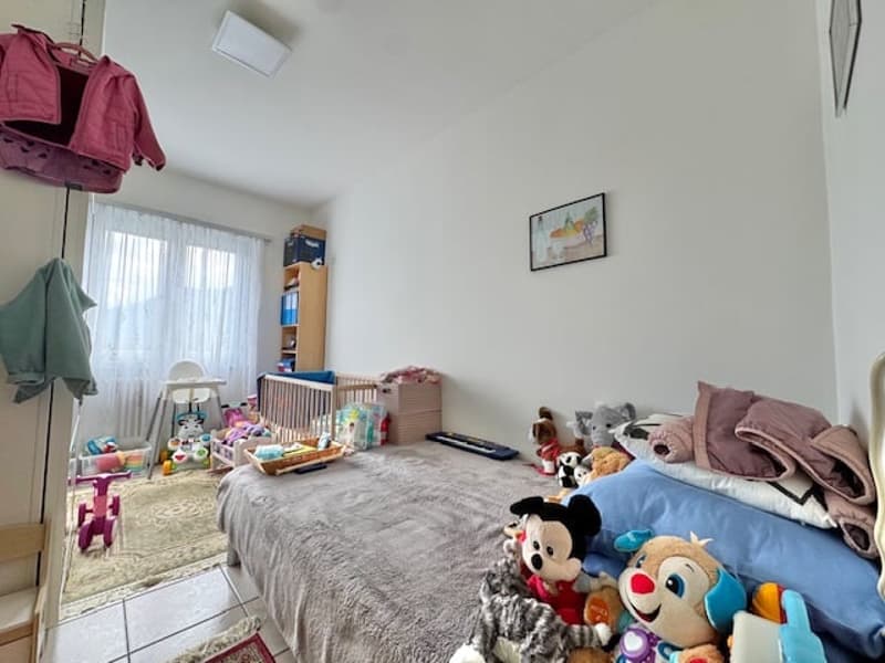 Bedroom with a bed, toys, and storage units. The room has a cozy and lived-in feel with various personal items and decorations.