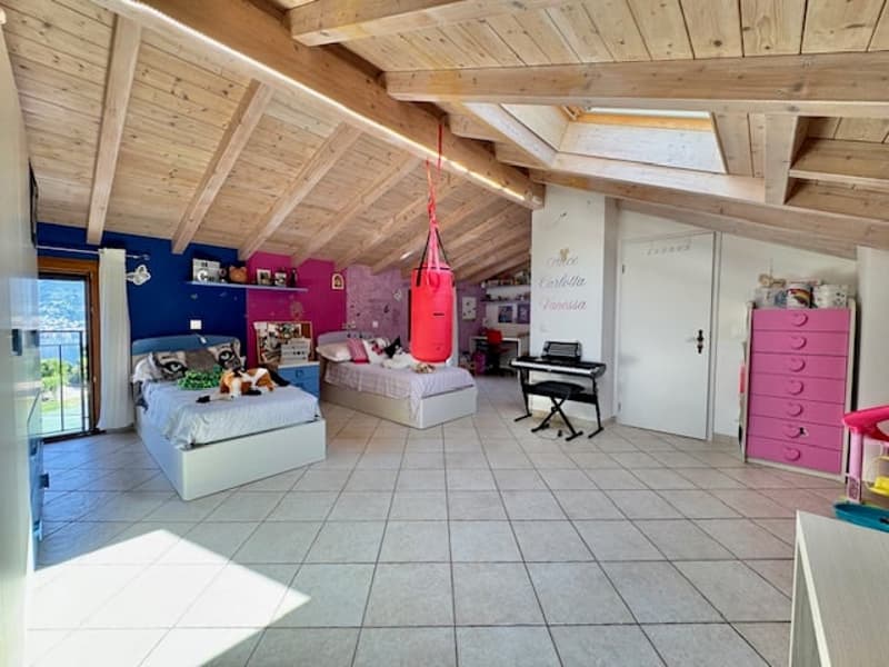Spacious attic bedroom with wooden beamed ceiling, large windows, sofa, punching bag, dresser, and musical equipment
