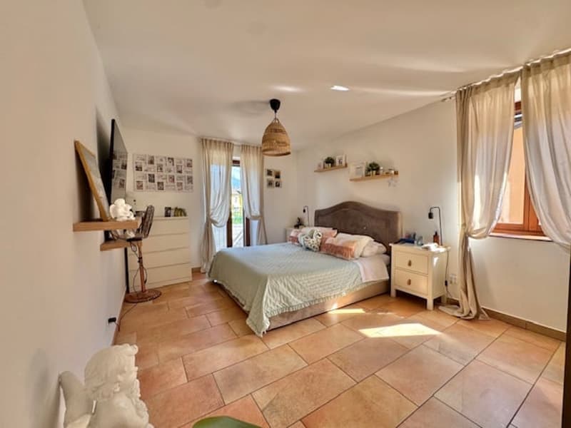 Spacious bedroom with tile flooring, large bed, dresser, nightstands, and a private washing machine