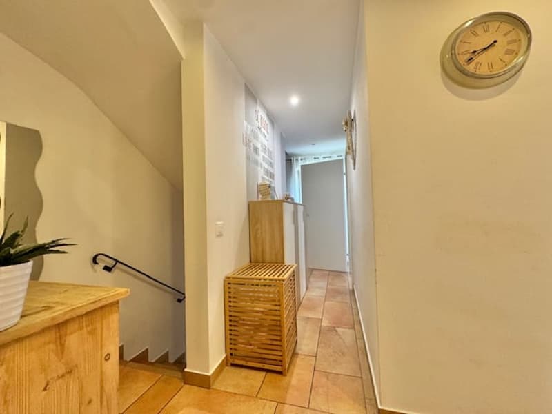 Hallway with wooden furniture, a washing machine, and a wall clock.