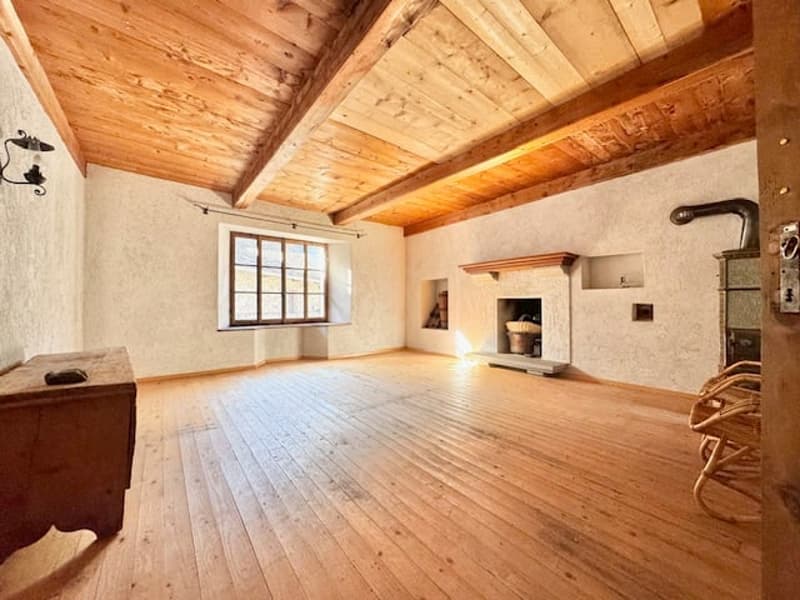 Large open space with wooden ceiling and floor, white walls, and a fireplace