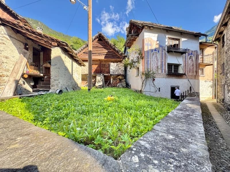 Traditional stone houses with wooden roofs, grassy courtyard, cobblestone path
