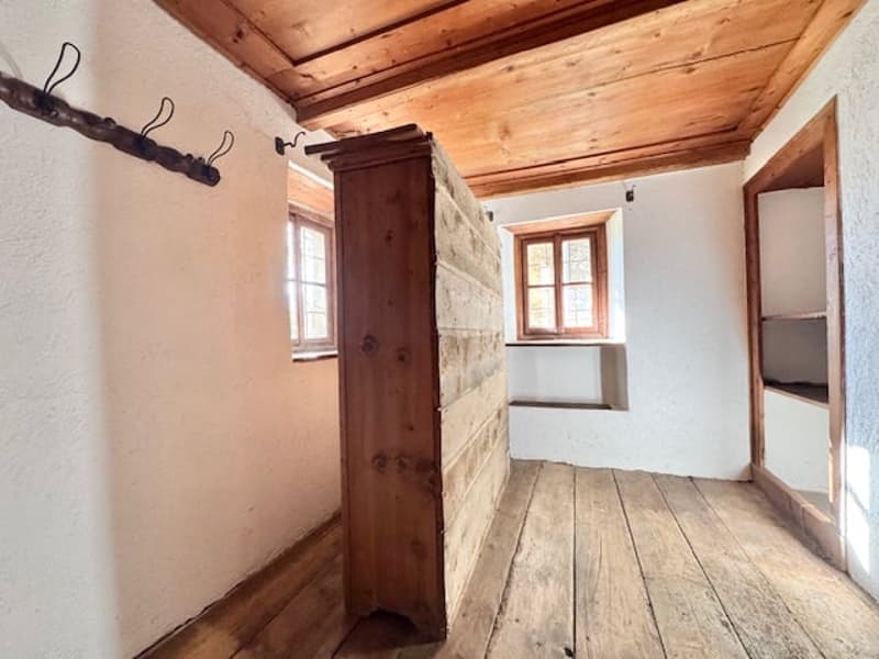 Rustic interior with wooden walls and ceiling, wooden floor, and a wooden cabinet or wardrobe in the corner.