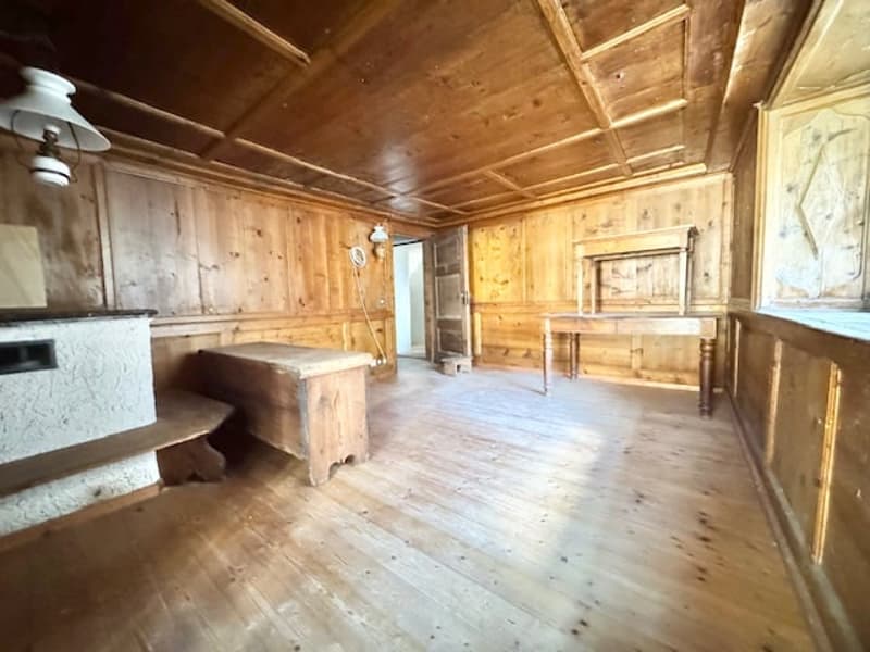 Rustic wooden cabin interior with exposed wood walls and ceiling, hardwood floors, and a fireplace.