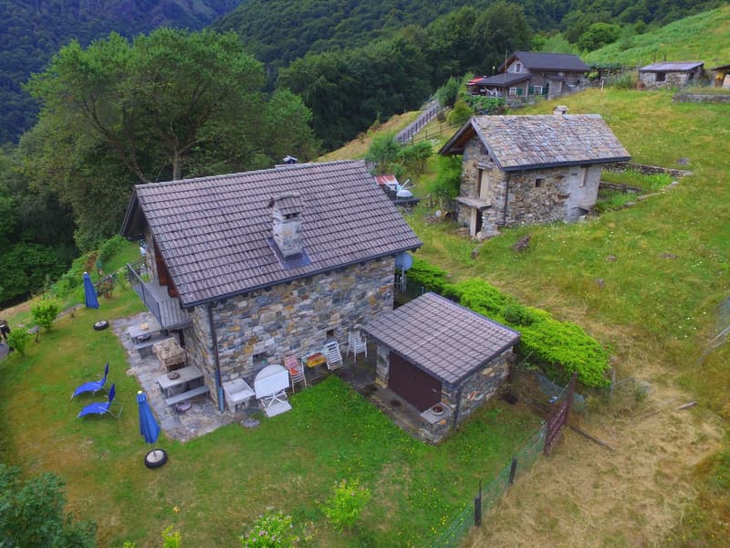 detached stone house, multiple chimneys, fenced yard, garden with patio, garage, outdoor seating, small pond