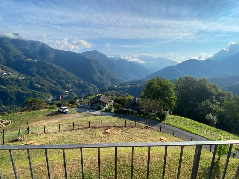 panoramic view, green field, mountains, road, houses, fenced area, car parked, clear blue sky
