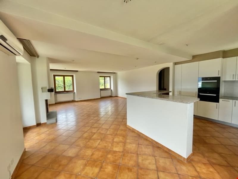 open space with kitchen island, large windows, tiled floor, white cabinets, black oven