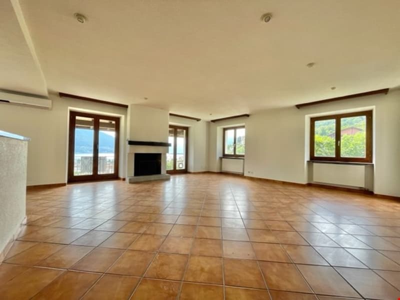 Empty room with brown tile flooring, white walls, fireplace, large windows, sliding glass doors