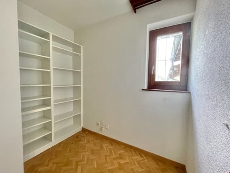 empty room with white walls, large window, wooden floor, white shelf, power outlets