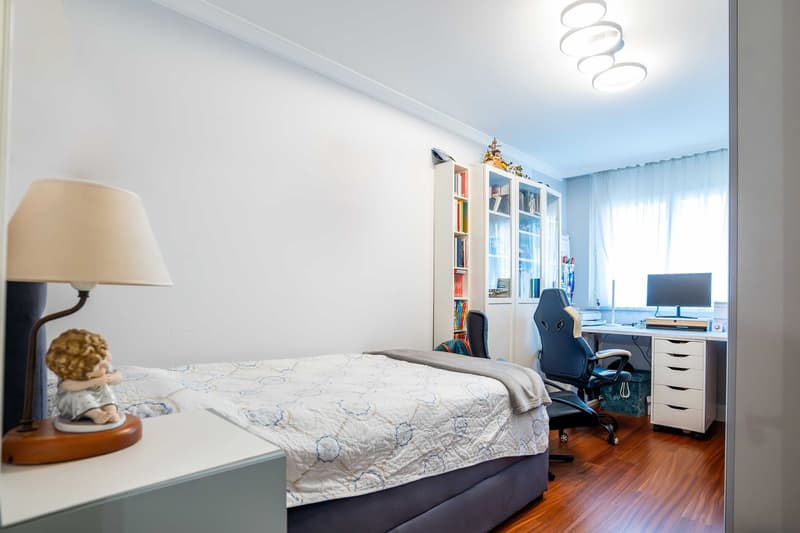 Bedroom with bed, lamp, nightstand, bookcases, chair, desk, computer, curtains