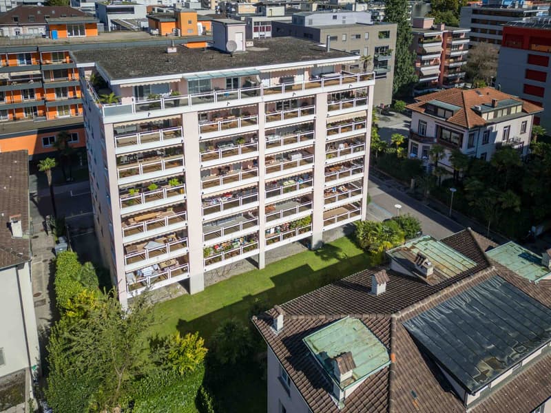 high-rise building, many balconies, surrounded by green area and other buildings