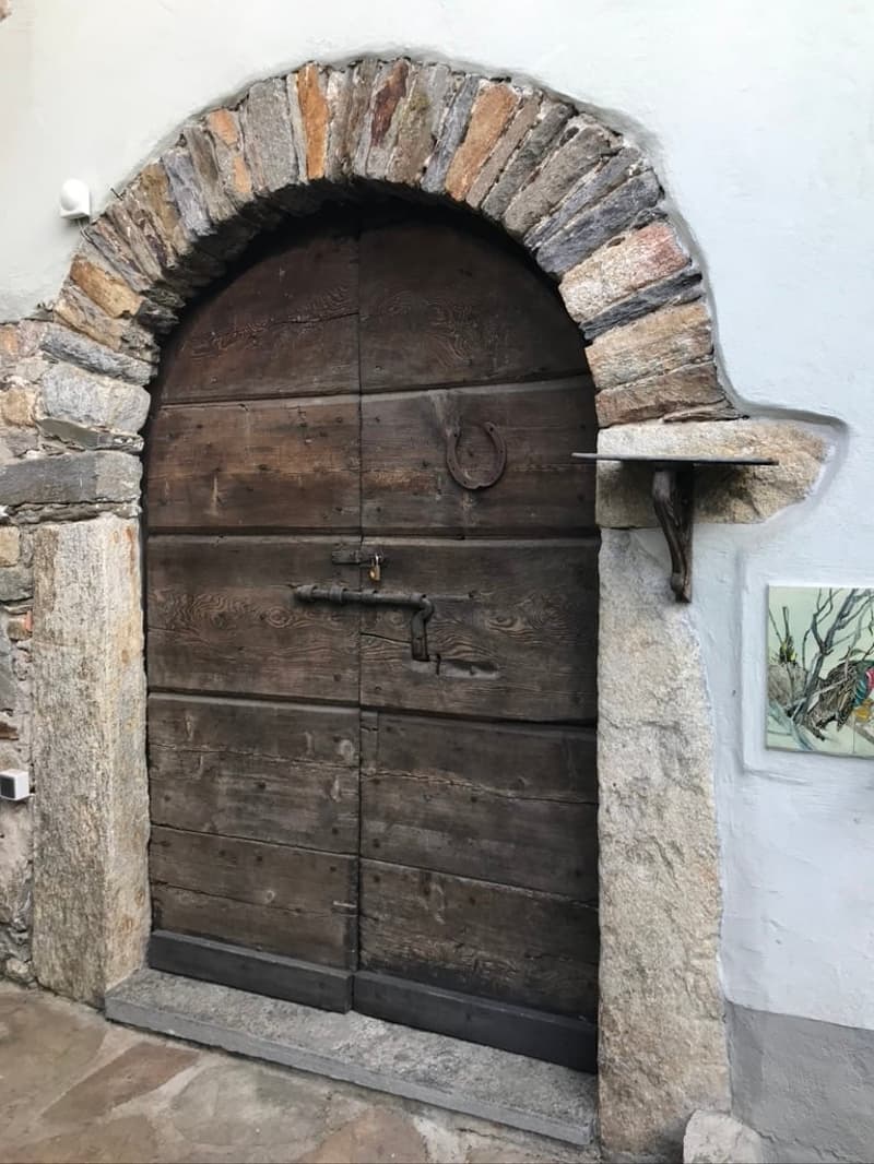 large wooden door with arch on top and iron railing attached to the stone wall