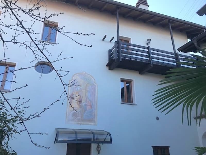 white stucco house, with several windows, balcony, religious painting, covered entrance