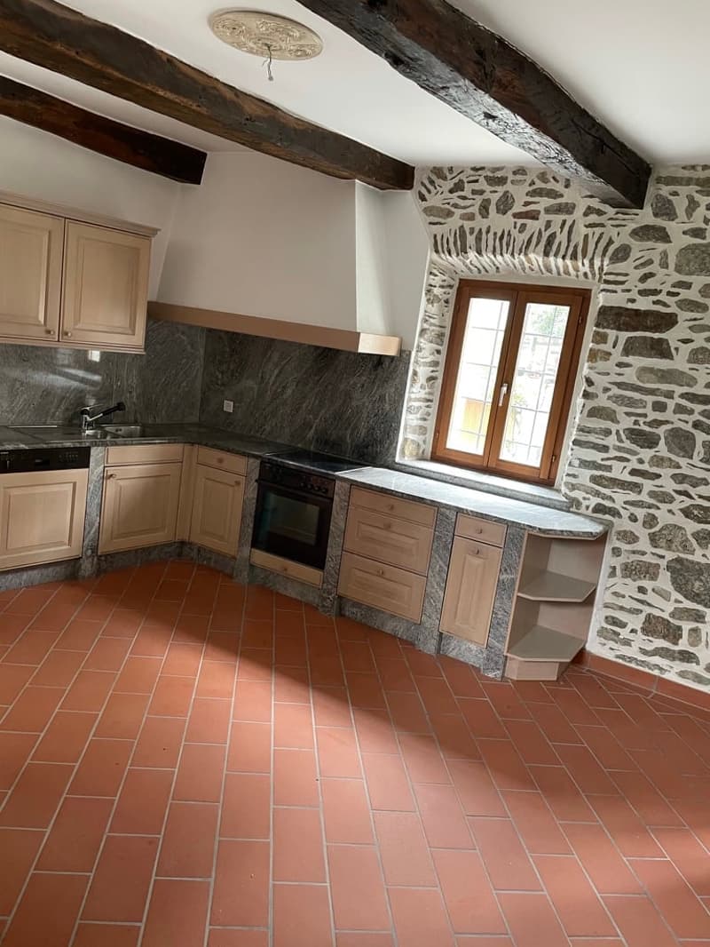 kitchen with red tiles floor, granite countertops, oven, dishwasher, sink with faucet, cabinets, stone wall, window