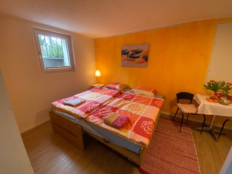 Bedroom with a double bed, nightstands, bedside lamps, floral bedding, window with view, and a dining table with flowers.