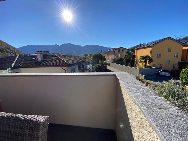 terrace with wicker chairs, white painted wall, beautiful sunlit view of mountains