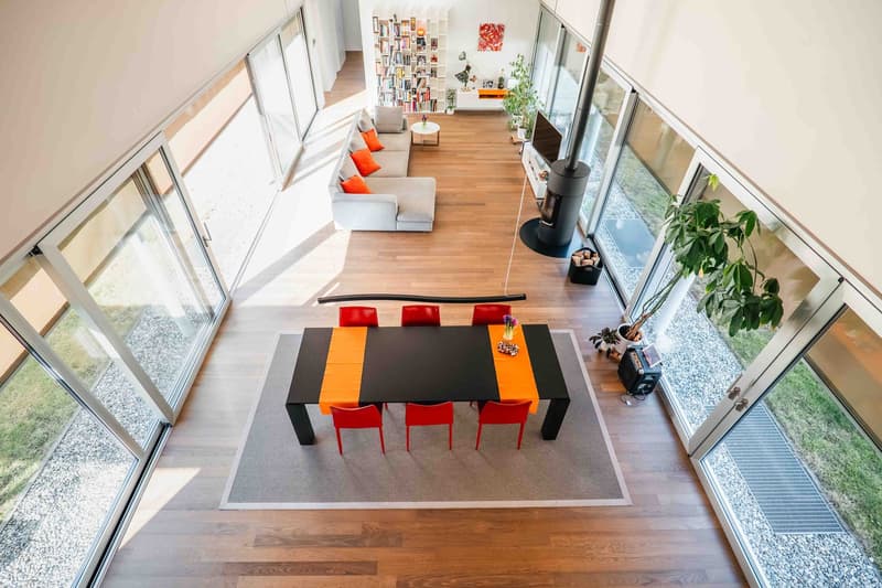 Open floor plan with living and dining area, modern style, large glass windows, wooden floors