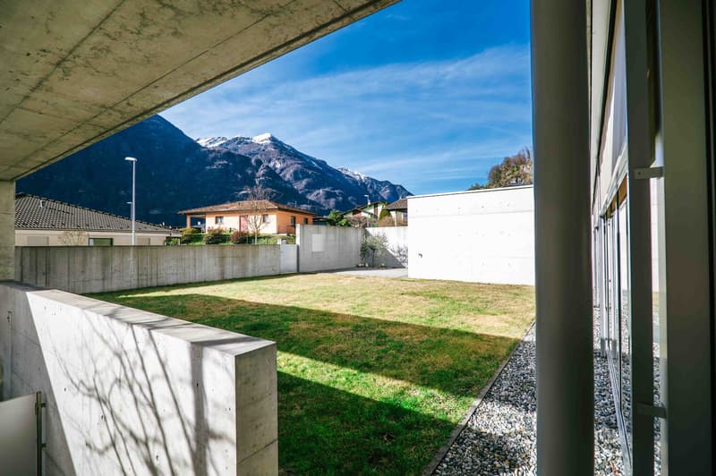 concrete wall, small grassy area, gravel path, distant mountains
