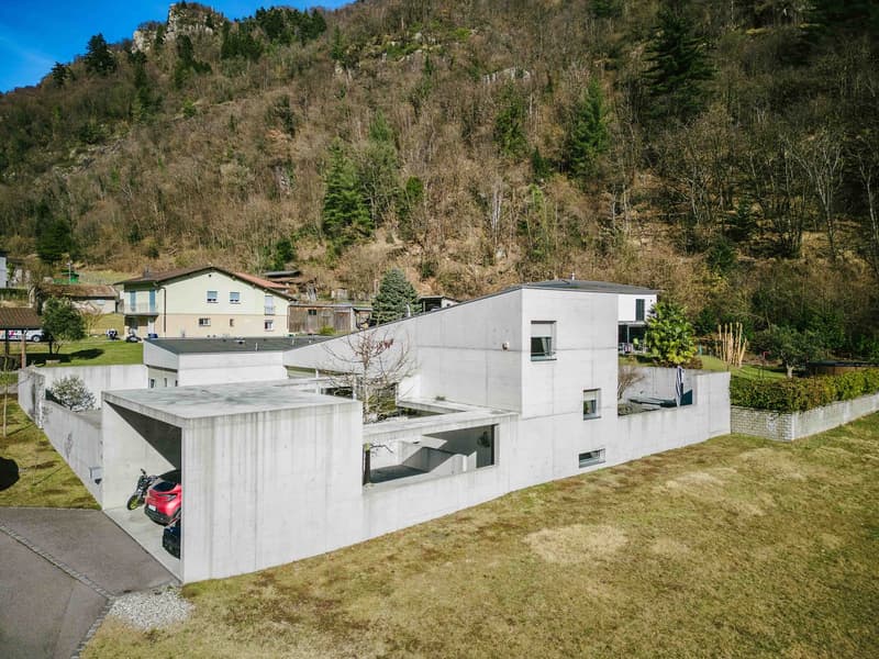 Concrete building, mountain background, 2 car garage, car parked