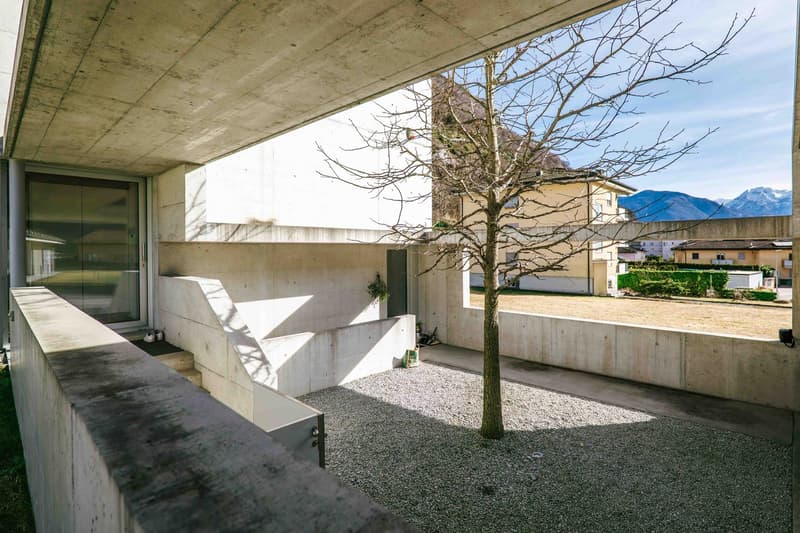 modern architectural concrete structure, exterior walkway, gravel ground, concrete balustrade, view of mountain landscape