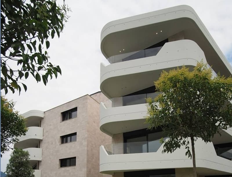 white exterior, multiple balconies, modern architecture, multiple windows, beige lower part