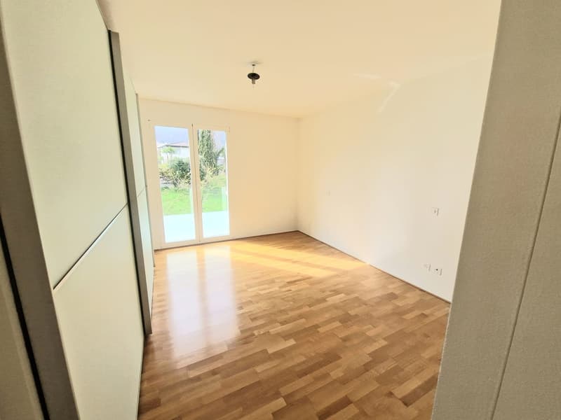 empty room with white walls, wooden floor, sliding glass door leading to outside, ceiling light fixture