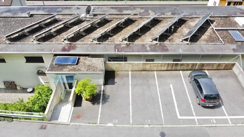 Multi-story building with a parking lot in the front, solar panels on the roof, and landscaping around the entrance.