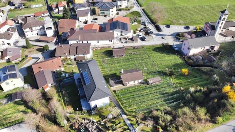 Aerial view of a small village with residential houses, agricultural fields, and a church tower visible.