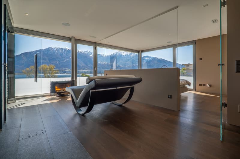 modern room with large windows, wooden floor, black leather lounge chair, fireplace, glass walls