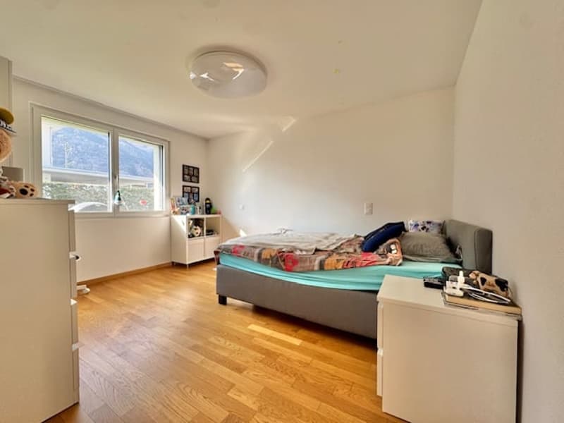Bedroom with bed, nightstand, cabinet, window, wooden floor, ceiling lamp, and view of mountains