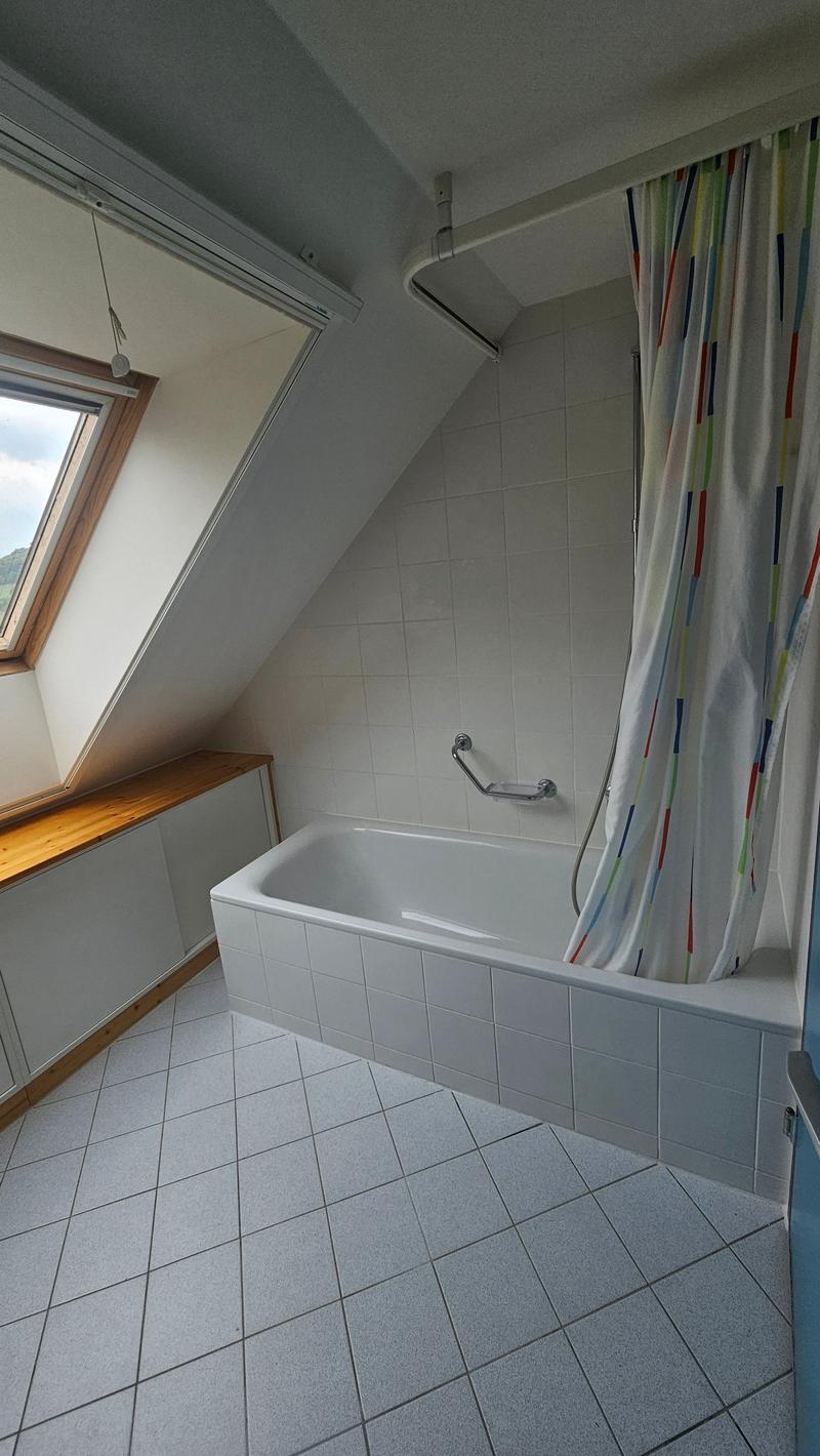 Bathroom with tiled floor, white bathtub, and colorful shower curtain