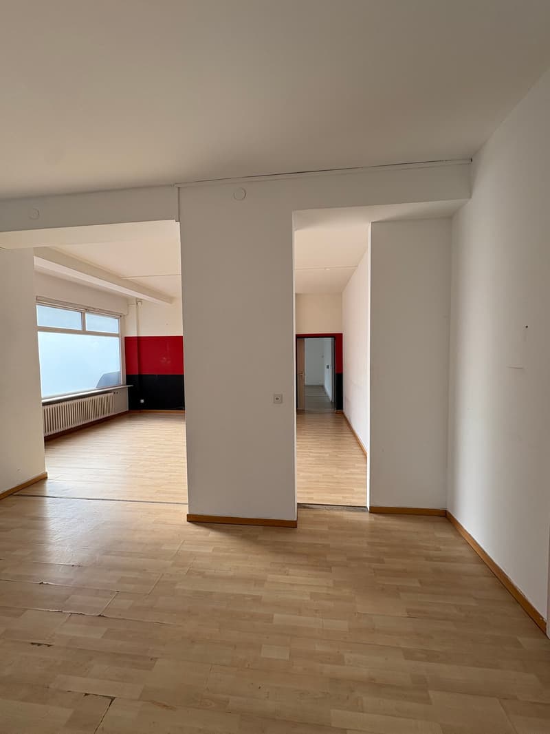 empty room with white walls and wooden floors, windows, pillar, and door