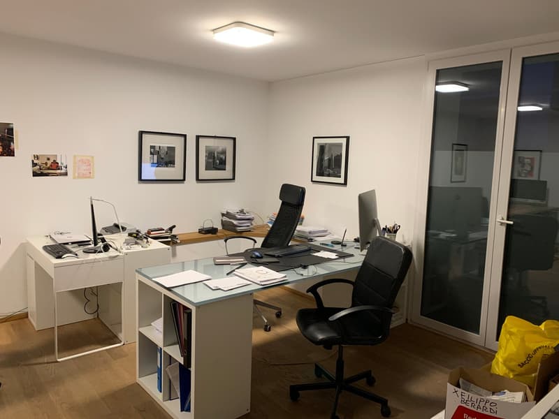 Two desks, two office chairs, monitors, books, shelves, floor lamp, door