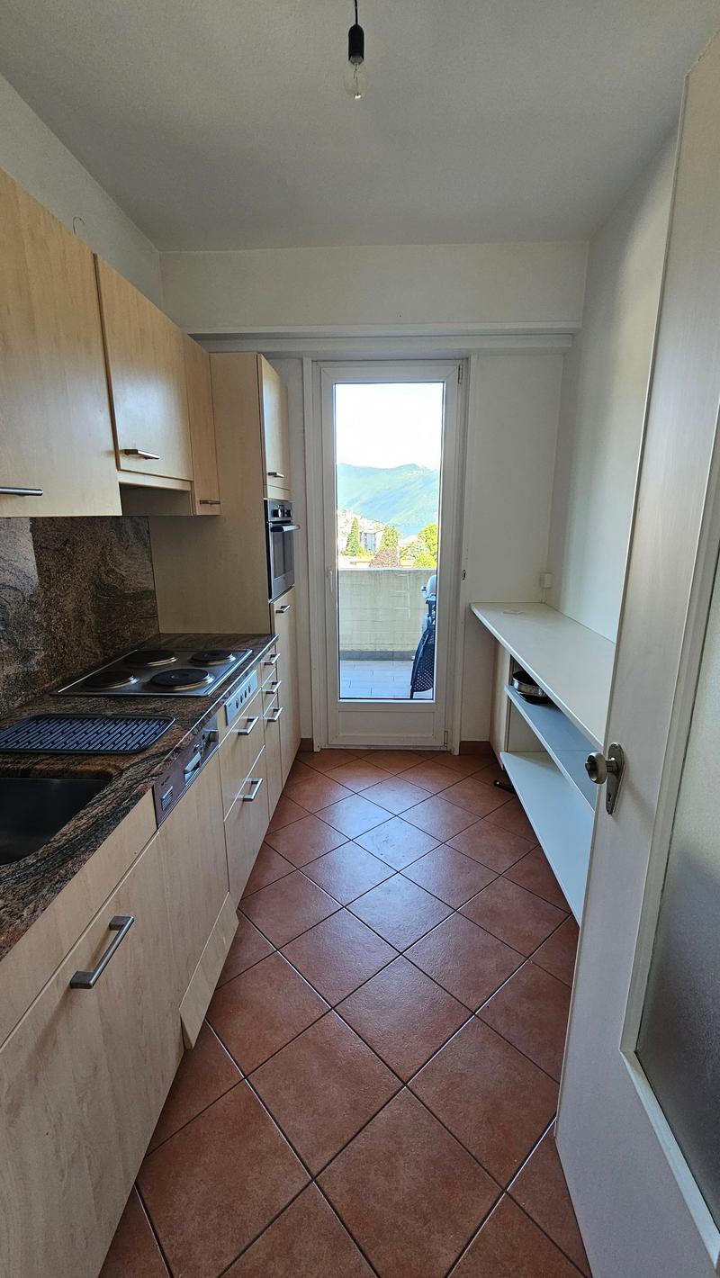 modern kitchen with tiled floor, marble countertop, electric stove, oven, dishwasher, cabinets, door to balcony