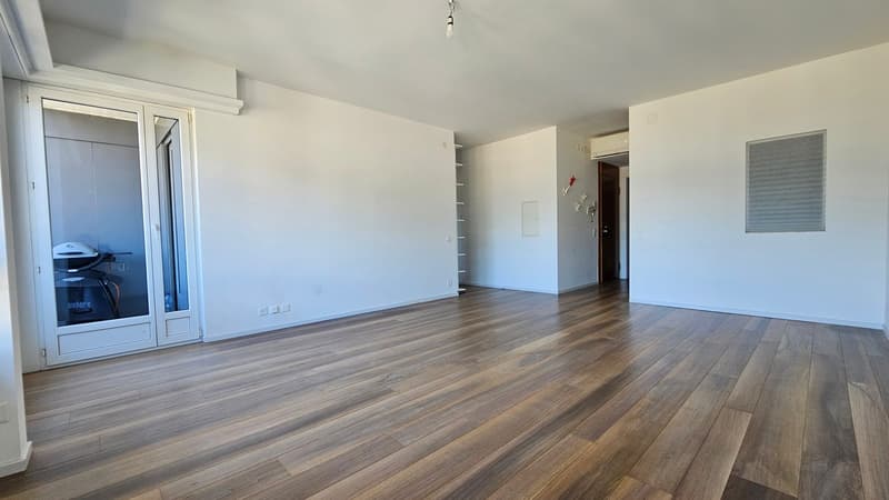large empty room, wooden floor, white walls, white sliding doors, balcony with treadmill