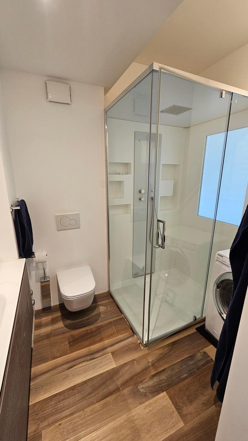 glass shower, toilet, white flooring, washing machine
