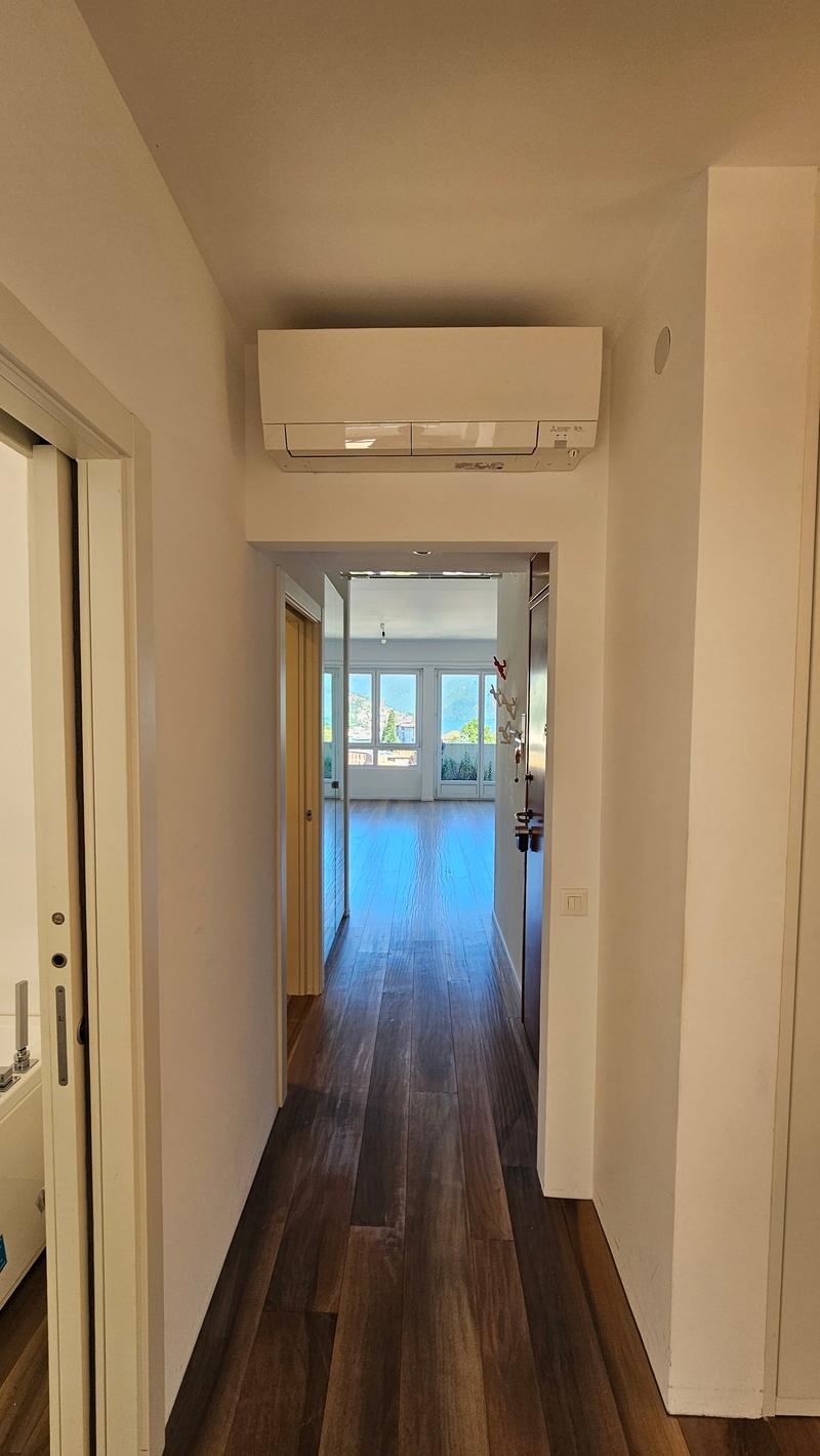 white walls, wooden floor, hallway leading to rooms, mounted AC unit