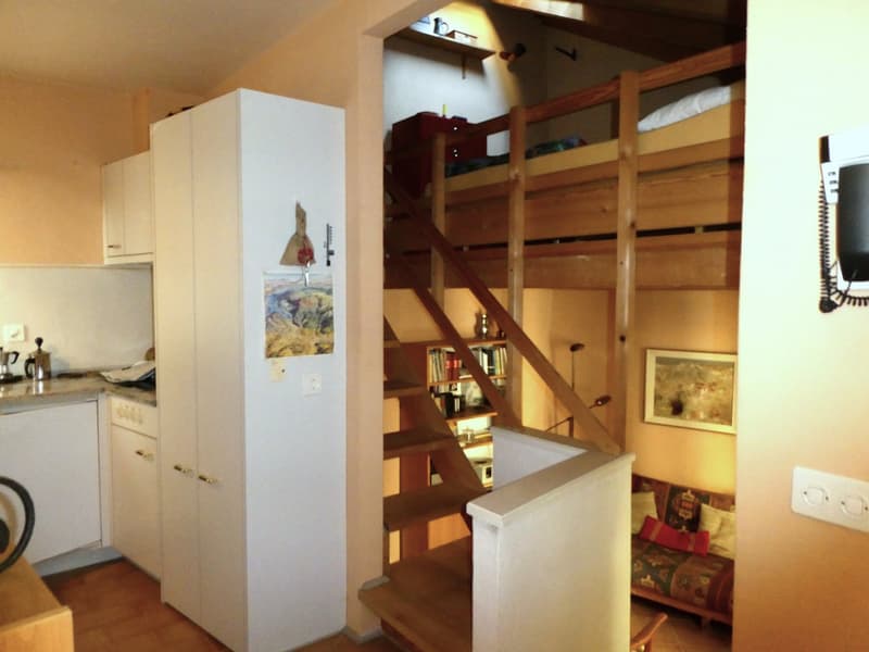 kitchen with white cabinets, wooden floor, bunk bed, staircase, couch, picture frame