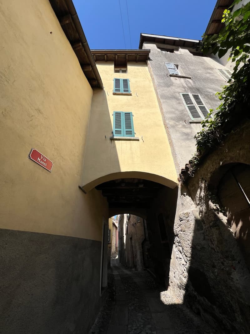 Old building with yellow walls, arched entrance, blue shutters, street sign