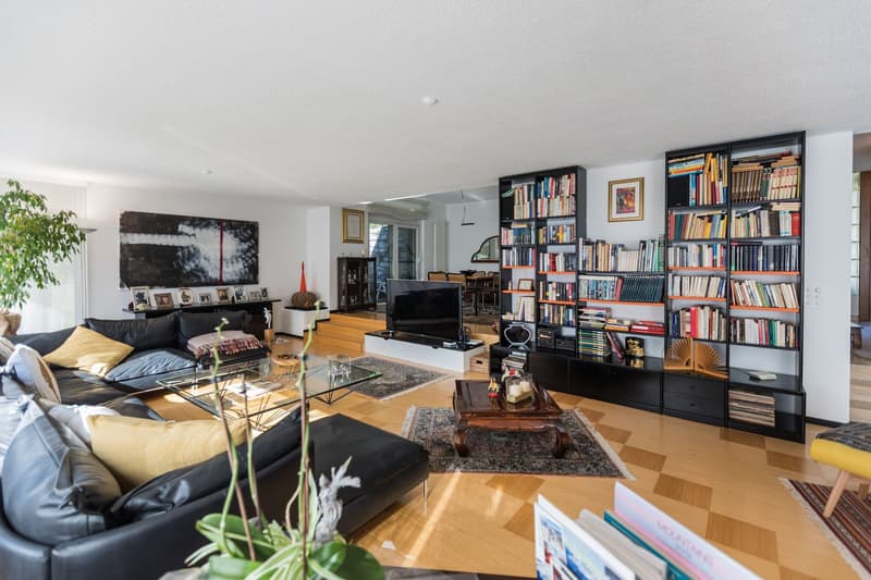 modern leather couch, glass coffee table, TV, wooden floor, wooden shelves with books
